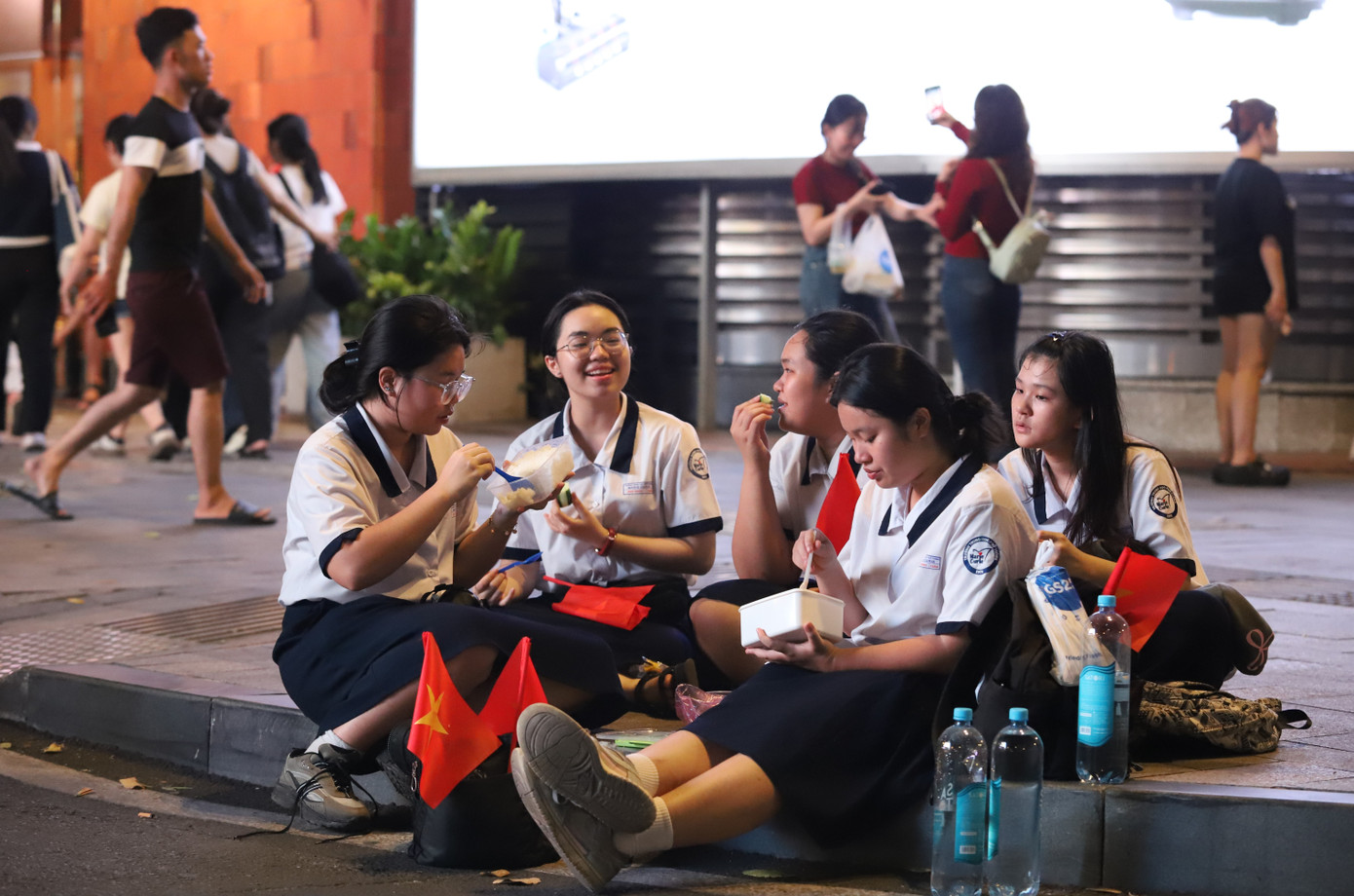 Nhóm 5 nữ sinh Trường THPT Marie Curie có mặt ở khu vực đường Phạm Ngọc Thạch chờ đoàn diễu binh. Nhóm bạn cho biết, ngay khi vừa hoàn thành bài thi cuối kỳ môn Văn và Anh văn liền đến đây chờ xem. Biết có thể sẽ xem trong thời gian dài nên một số bạn đã mang theo cơm để ăn. &quot;Dù có thể đi lại mất công chút nhưng tụi em không xem đây là vấn đề khó khăn gì, với tinh thần xem được hay không cũng vui. 50 năm mới có một lần như vậy nên rất đón chờ xem buổi lễ&quot;, em Nguyễn Ngọc Hải Anh chia sẻ.
