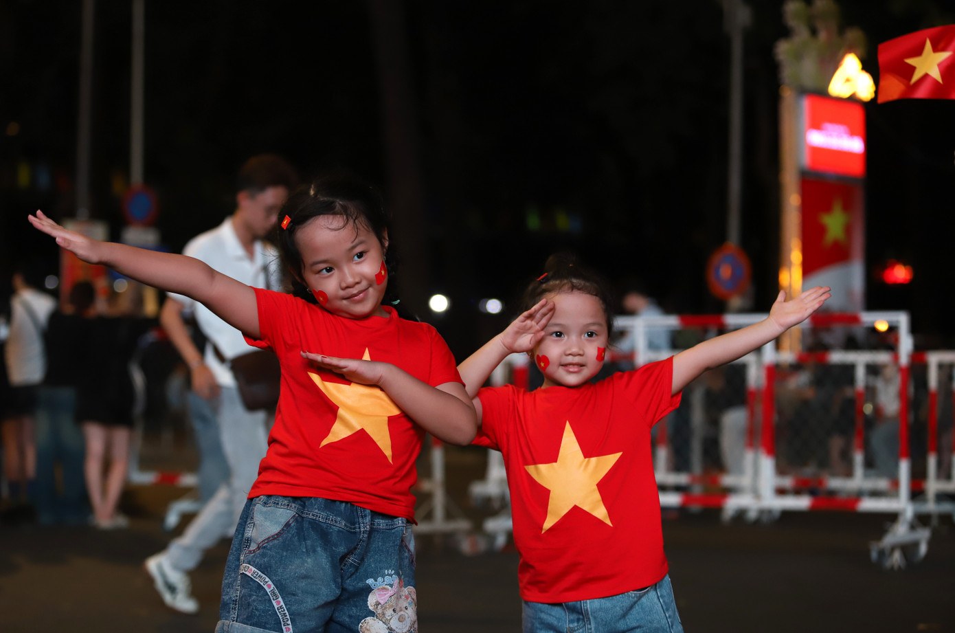 Hai em nhỏ được phụ huynh đưa ra phố vui chơi, hòa trong không khí hân hoan trước ngày hội lớn.