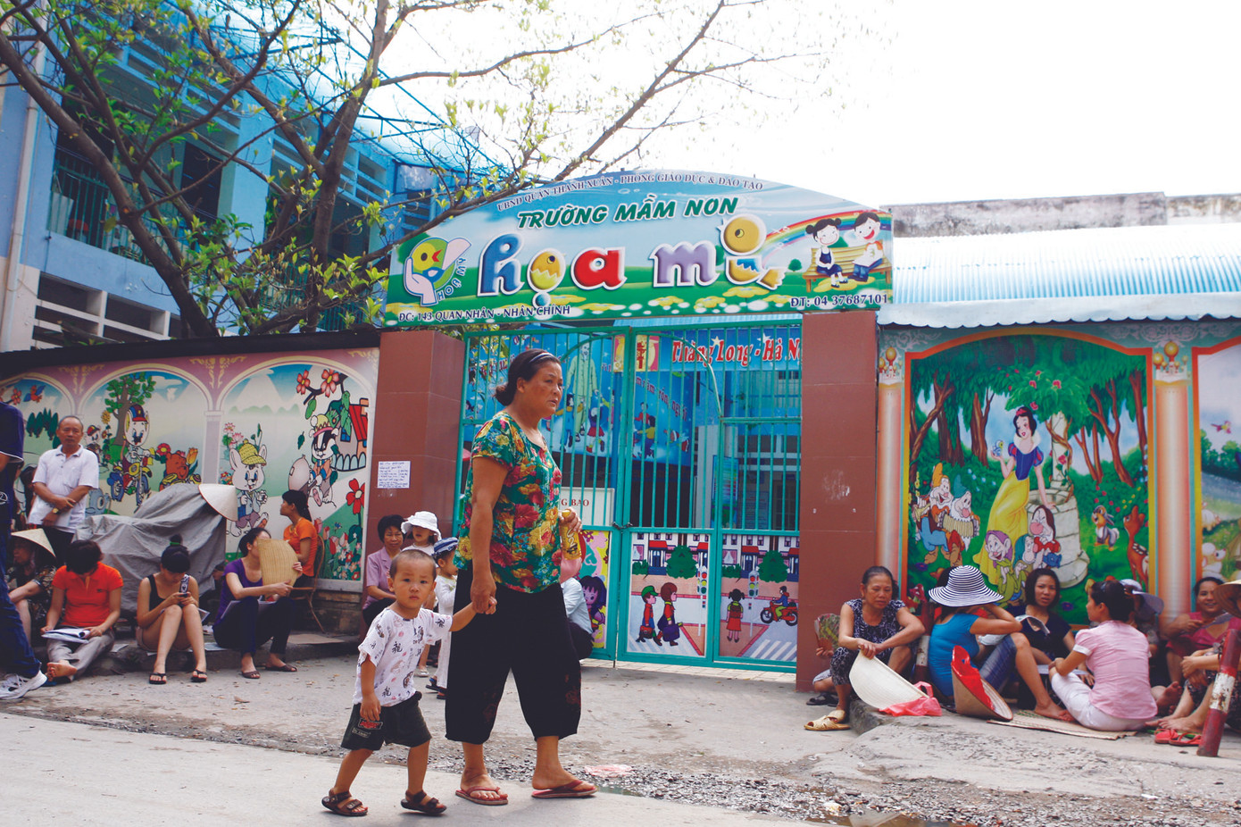 Ngồi vật vã ngoài cổng trường mầm non để nộp đơn xin học - Ảnh: Hồng Vĩnh