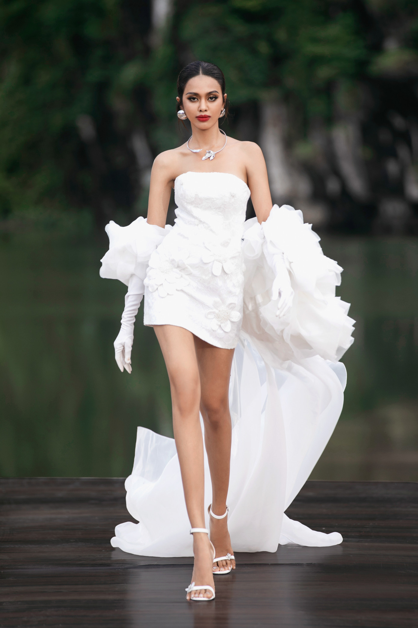 Đại diện Campuchia - Leakena In gây ấn tượng khi trình diễn thiết kế cúp ngực màu trắng được đính kết hoa cầu kỳ dọc thân váy. Cô là Á hậu 2 tại Hoa hậu Hòa bình Campuchia 2023. Leakena In được fan Việt biết đến và yêu mến khi đăng tải clip hát theo ca khúc Em là con gái miền Tây. Người đẹp từng đại diện Campuchia tham dự Hoa hậu Siêu quốc gia 2022 nhưng không giành thành tích.