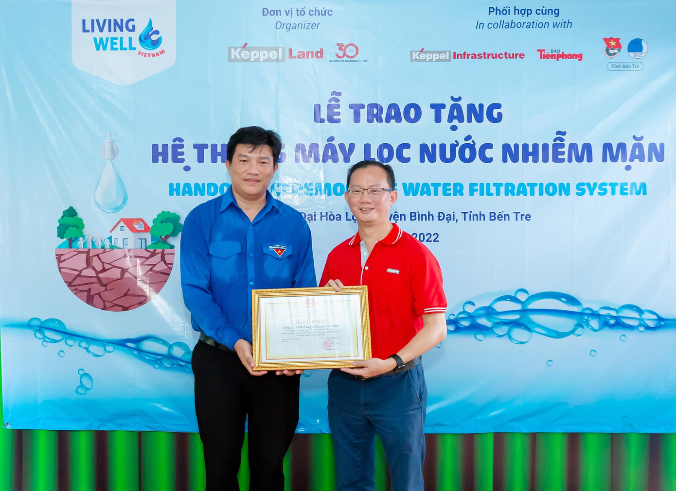 Ông Phạm Bùi Phi Líp (trái) trao bằng khen của UBND Tỉnh Bến Tre cho Ông Joseph Low (phải).