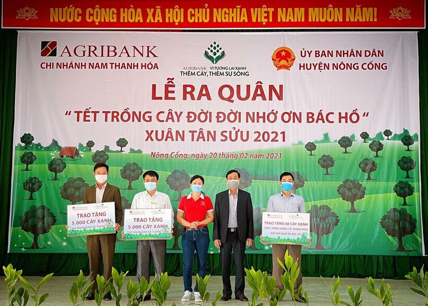 Bà Trinh Thị Kim Liên (giữa) - Phó Giám đốc Agribank Nam Thanh Hóa trao tặng tượng trưng người dân các xã Tượng Lĩnh, Thăng Bình mỗi xã 5.000 cây keo giống và trồng 60 cây bóng mát bằng lăng tím tại thị trấn Nông Cống