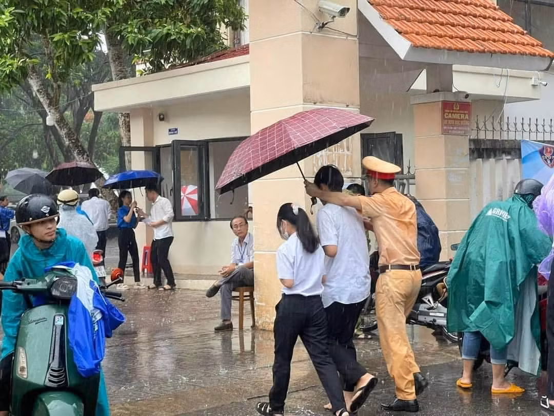 Nhiều chiến sĩ không ngại ướt mưa để đảm bảo thí sinh được khô ráo. Ảnh: Nguyễn Mệt.