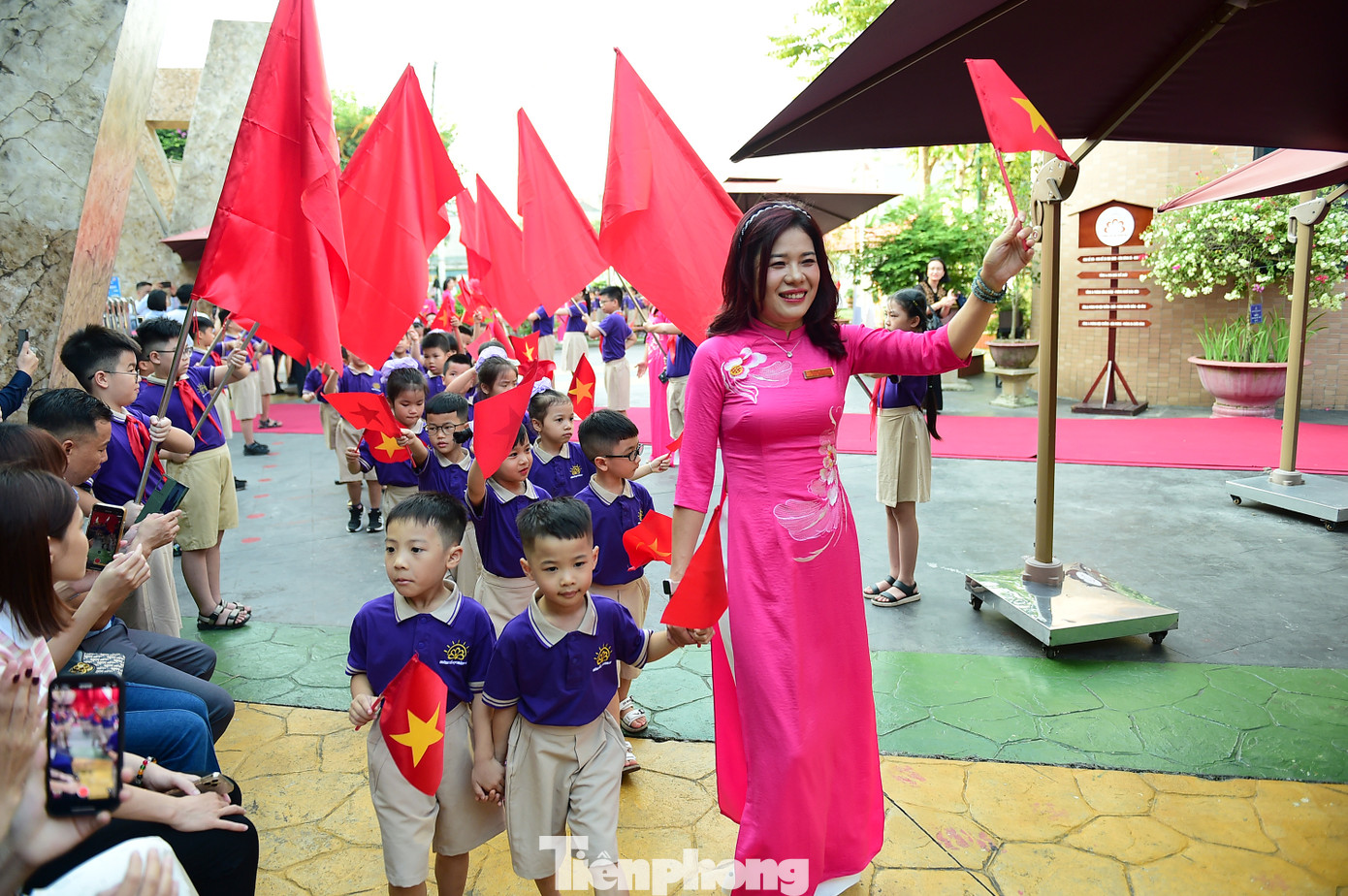 Lễ khai giảng năm học mới càng thêm đặc biệt với các bạn nhỏ bước vào lớp 1. Trong ảnh, các em học sinh lớp 1 trường Tiểu học Hoàng Mai (Hà Nội) tay vẫy cờ đỏ sao vàng và hoa, được giáo viên chủ nhiệm dẫn bước vào trường. Ảnh: Xuân Tùng