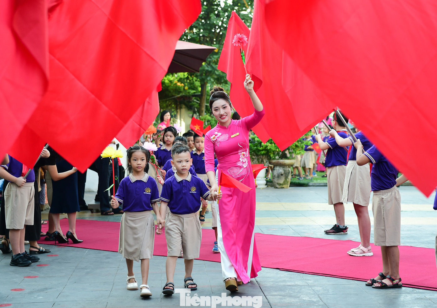 Lễ khai giảng năm học mới càng thêm đặc biệt với các bạn nhỏ bước vào lớp 1. Trong ảnh, các em học sinh lớp 1 trường Tiểu học Hoàng Mai (Hà Nội) tay vẫy cờ đỏ sao vàng và hoa, được giáo viên chủ nhiệm dẫn bước vào trường. Ảnh: Xuân Tùng