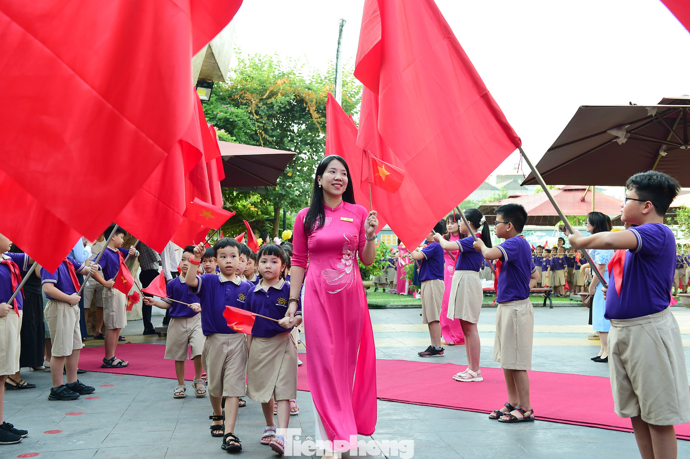 Lễ khai giảng năm học mới càng thêm đặc biệt với các bạn nhỏ bước vào lớp 1. Trong ảnh, các em học sinh lớp 1 trường Tiểu học Hoàng Mai (Hà Nội) tay vẫy cờ đỏ sao vàng và hoa, được giáo viên chủ nhiệm dẫn bước vào trường. Ảnh: Xuân Tùng