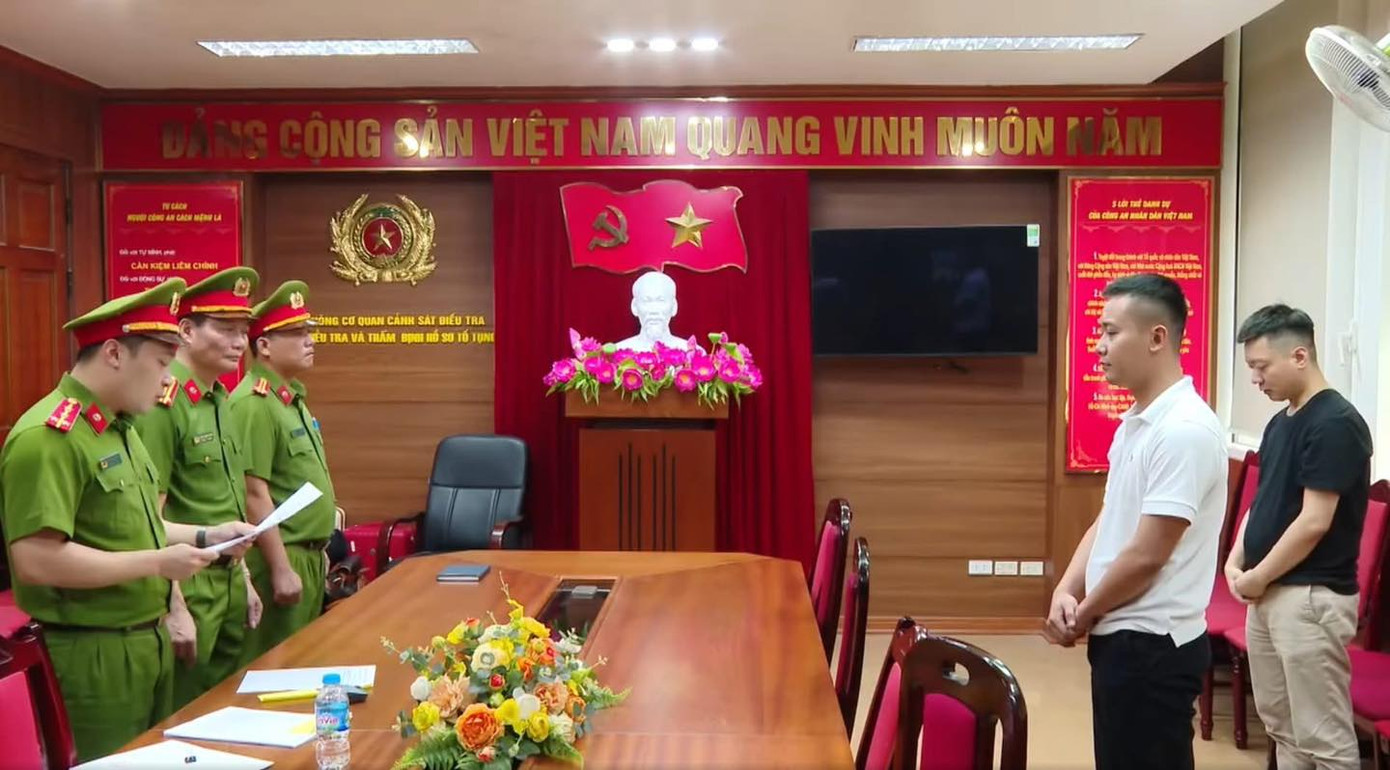 Hằng Du Mục, Quang Linh Vlogs nghe công an đọc lệnh khởi tố, bắt tạm giam. (Nguồn: Thời sự VTV)