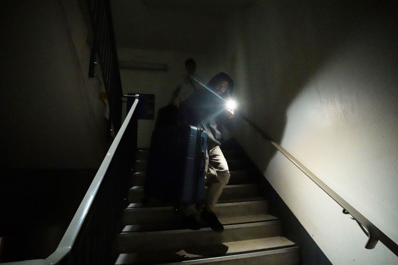 Hình ảnh hành khách bị mắc kẹt đang dò dẫm đi xuống cầu thang bộ để đến bãi đậu xe của sân bay Heathrow, thang máy không hoạt động do mất điện. Ảnh: AP.