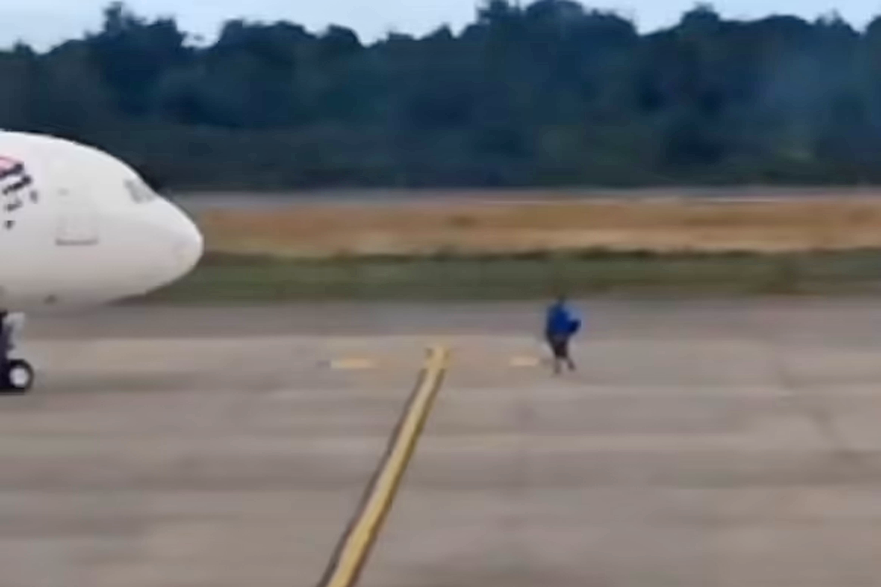 Người đàn ông bị nhân viên sân bay áp giải ra khỏi đường băng sau vụ việc. Ảnh: Daily Mail.