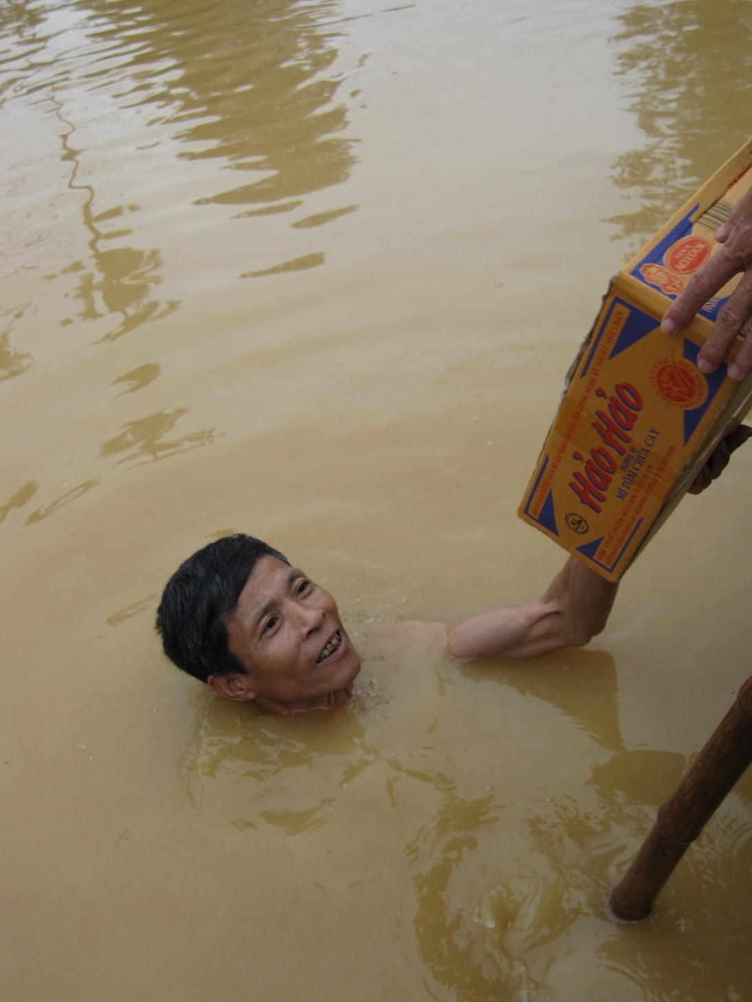 Ông Võ Bá Thiện, xã Gia Phố, Hương Khê bơi giữa dòng nước lũ nhận thùng mỳ của đoàn cứu trợ