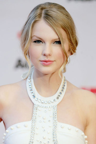 Taylor Swift trong sáng và tươi tắn như thiên thần với gương mặt trang điểm tông hồng đào, hai lọn tóc rủ hai bên rất ăn ý với chiếc váy trắng tinh khôi