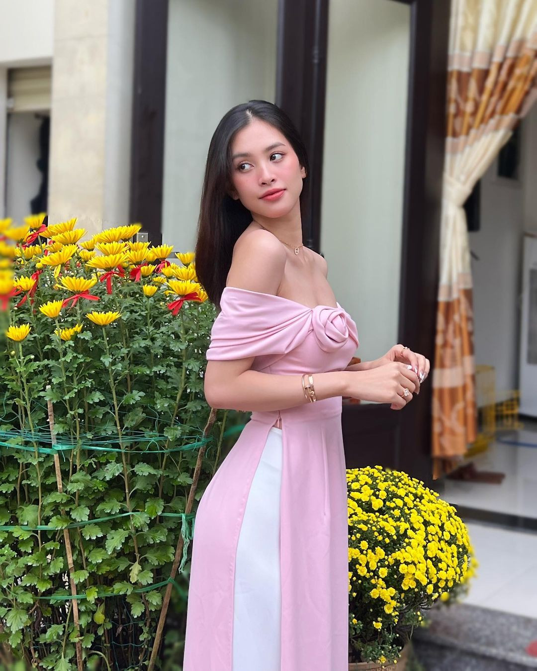 Hoa hậu Tiểu Vy chọn áo dài màu hồng trễ vai quyến rũ để mặc trong ngày đầu năm. Cô về đón Tết cùng gia đình ở Đà Nẵng. Do bận rộn công việc, sát ngày 30 Tết, Tiểu Vy mới về thăm nhà được.