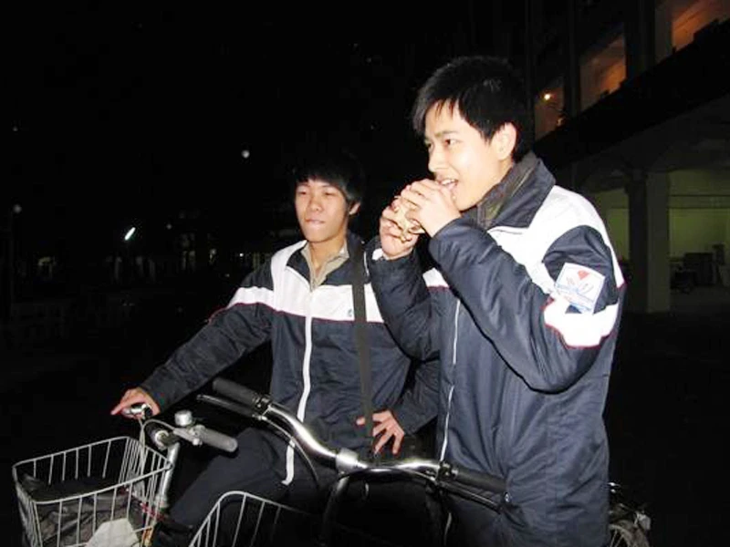 Hai học sinh lớp 10 Trường THPT Quang Trung -Hà Nội ăn chung một chiếc bánh mỳ sau khi tan học lúc 19h. Ảnh: Trường Phong