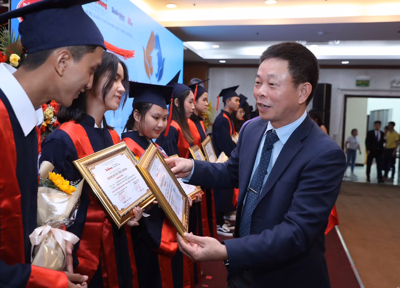Nhà báo Phùng Công Sưởng - Phó tổng biên tập Báo Tiền Phong trao hoa, học bổng và quà của Văn phòng Chính phủ cho sinh viên tại điểm cầu TP.HCM.
