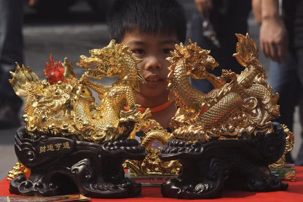 Cậu bé người Philipines đang ngắm nhìn hai chú rồng mạ vàng tại thủ đô Manila, Philippines. Ảnh: Chinadaily