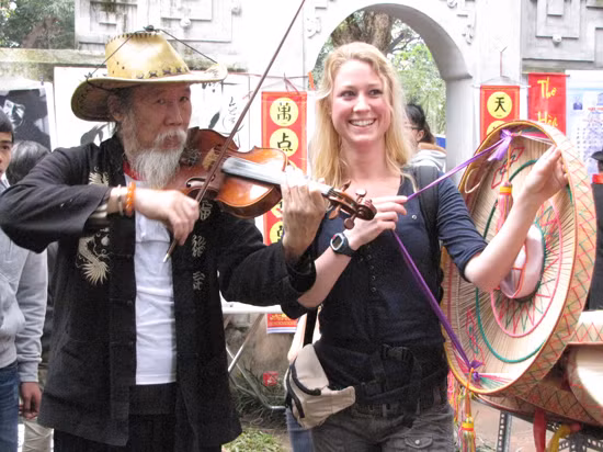 Một nữ du khách nước ngoài làm duyên với nói quai thao bên cạnh một nghệ sĩ Violon