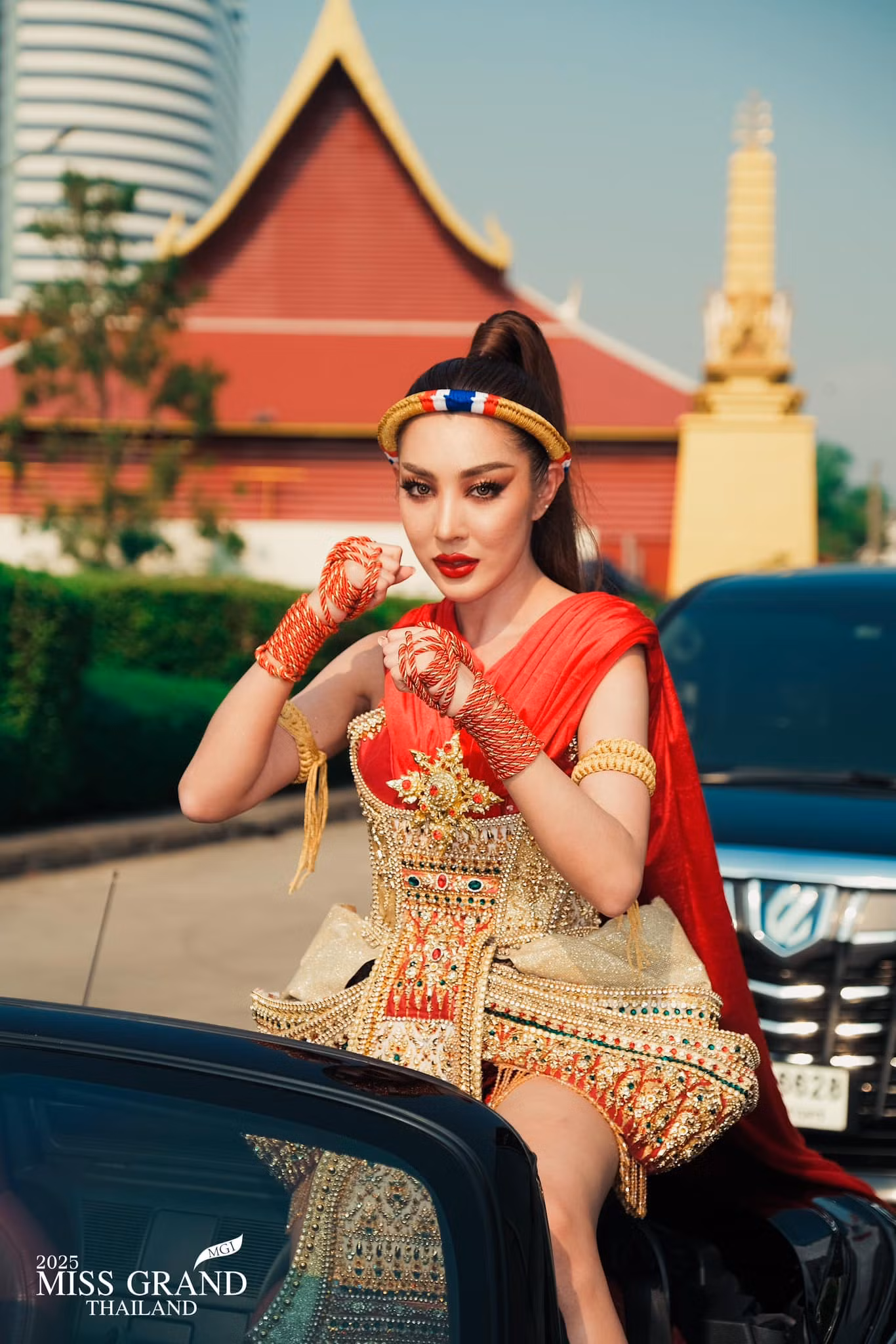Một người đẹp mặc trang phục dân tộc đại diện tỉnh của mình, ngồi trên xe mui trần đến nơi tập trung thí sinh.