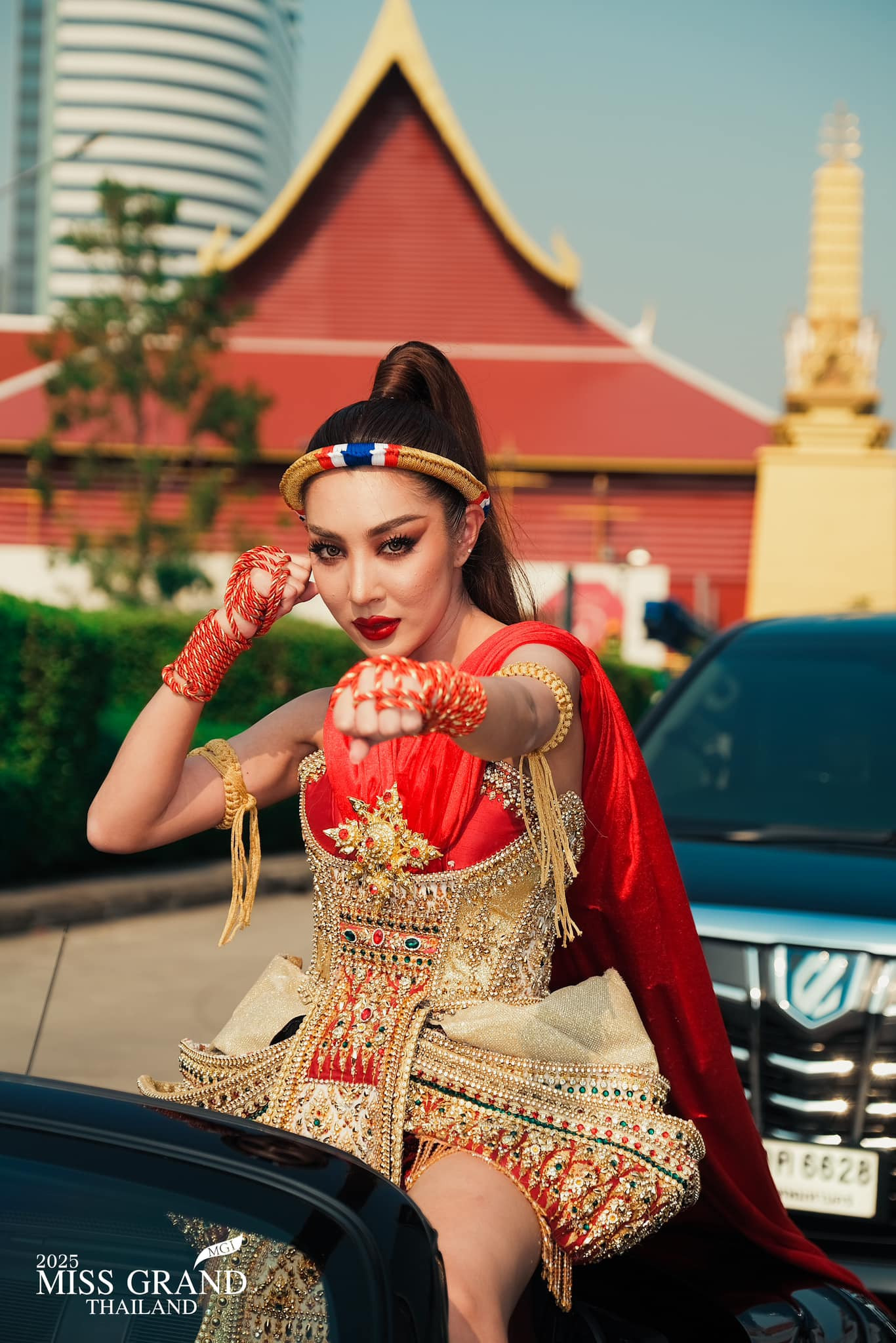 Một người đẹp mặc trang phục dân tộc đại diện tỉnh của mình, ngồi trên xe mui trần đến nơi tập trung thí sinh.