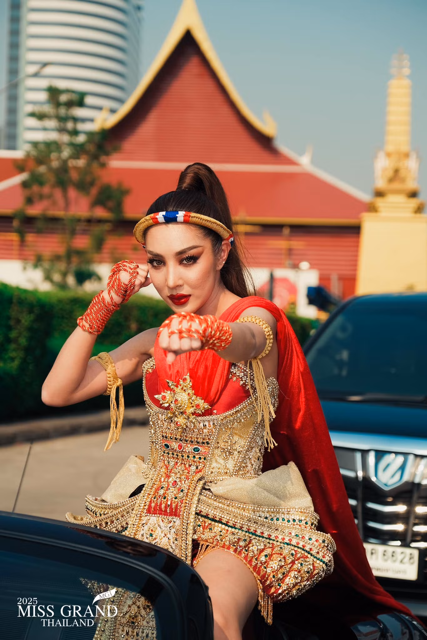 Một người đẹp mặc trang phục dân tộc đại diện tỉnh của mình, ngồi trên xe mui trần đến nơi tập trung thí sinh.