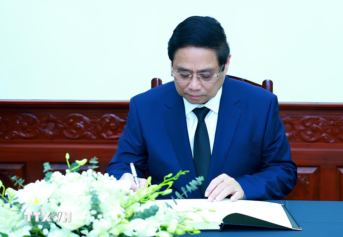 Thủ tướng Phạm Minh Chính ghi sổ tang chia buồn. (Ảnh: Dương Giang/TTXVN)
