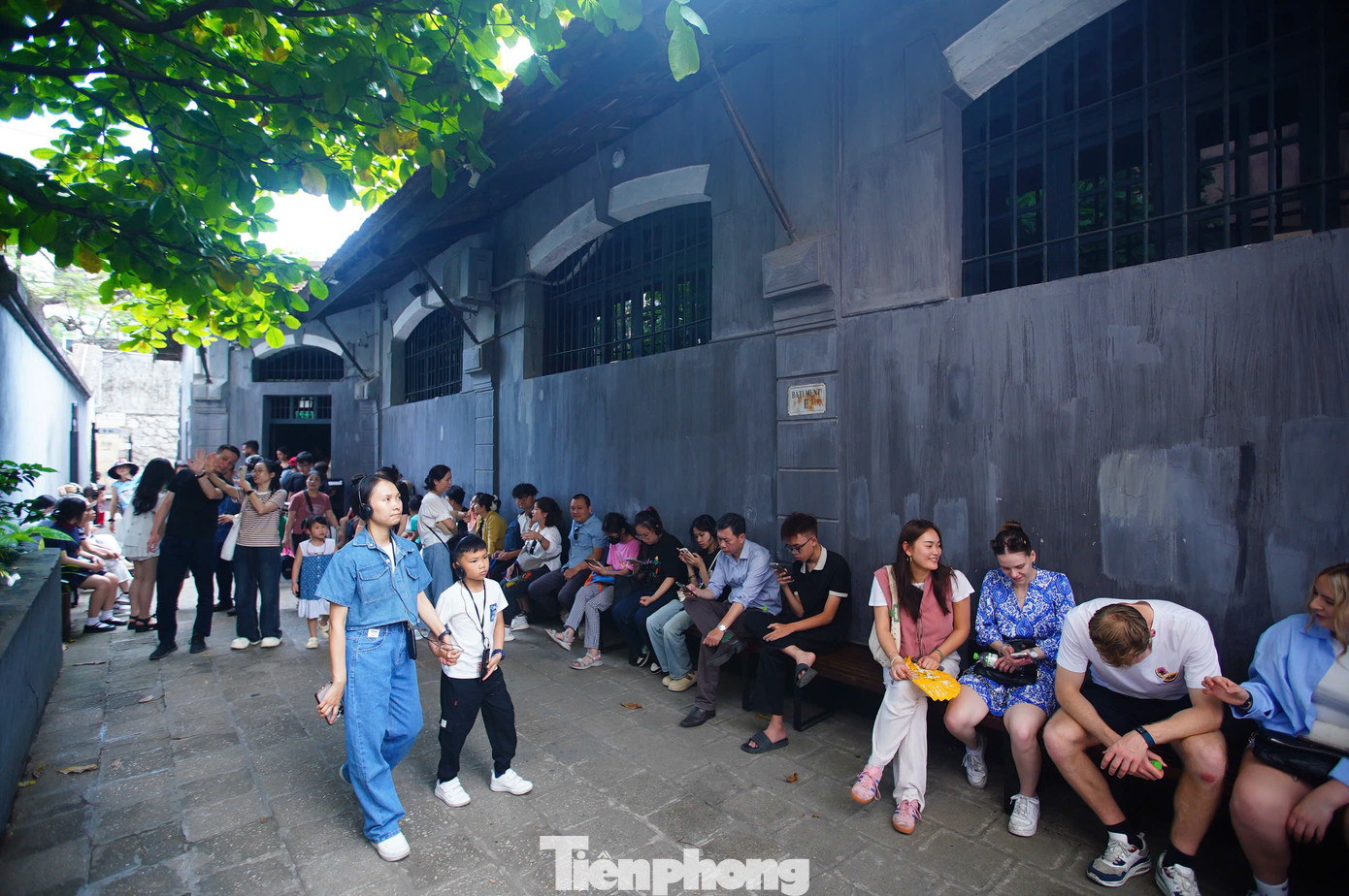 Hàng dài du khách nghỉ ngơi, đợi chờ trong khuôn viên di tích. Một số du khách phải đợi không gian trong nhà tù vãn khách mới có thể vào tham quan.