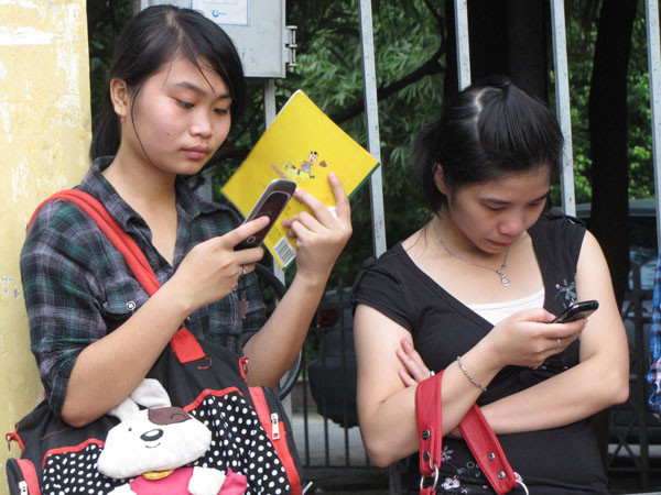 Sử dụng điện thoại trong thời gian chờ đợi. Ảnh: Trường Phong