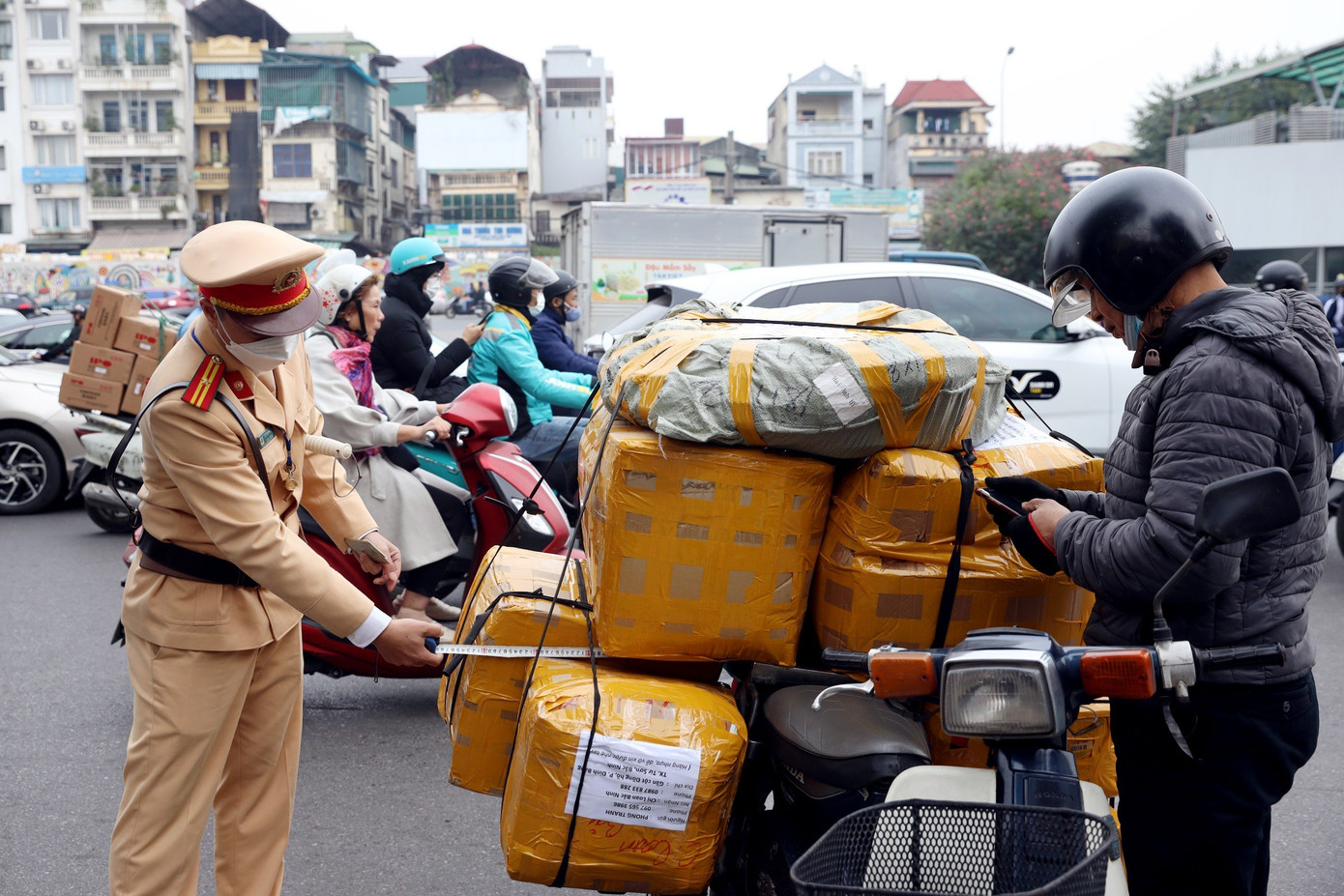 Xe máy chở hàng hóa cồng kềnh di chuyển trên đường.