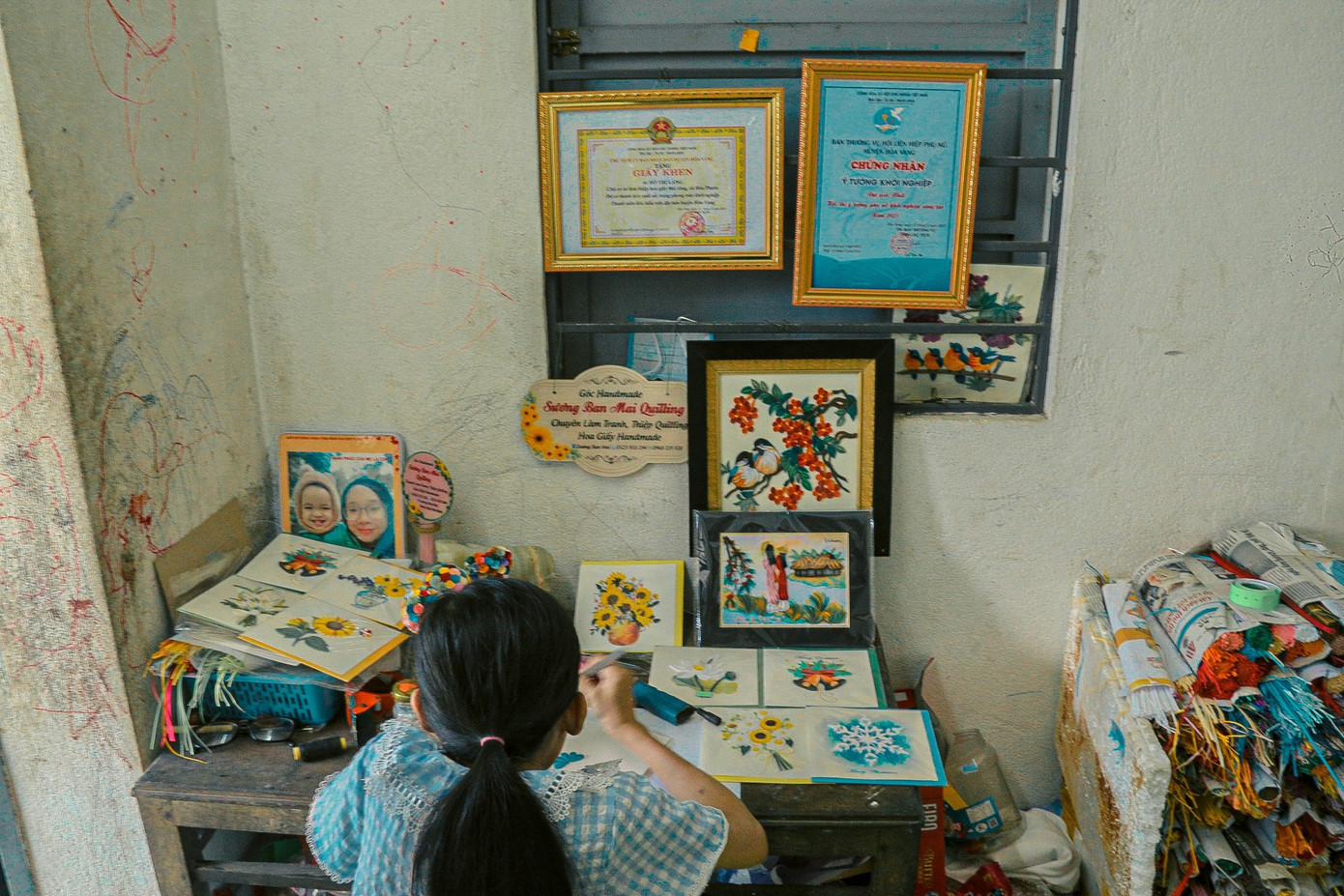 Ngôi nhà chưa đầy 10m2 của chị Hồ Thị Láng (thôn Cồn Mong, xã Hòa Phước) treo kín những bức tranh Tết bằng giấy xoắn - dòng tranh được tạo từ những sợi giấy nhiều màu cắt sợi gấp cuộn lại rồi khảm vào các bề mặt vật liệu khác nhau. Những ngày sát Tết, chị Láng phải làm liên tục ngày đêm để kịp giao cho khách đã đặt từ tháng trước.