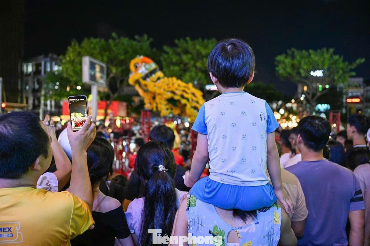 Các em nhỏ được bố mẹ dẫn đi chơi Trung thu, xem múa lân.