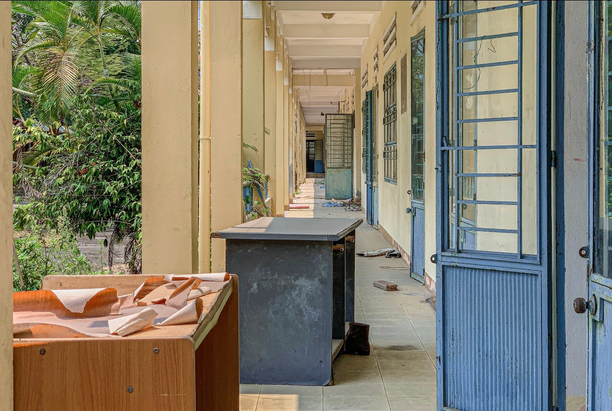 Phía bên ngoài hành lang nhiều bàn ghế vứt bừa bãi, lá cây phủ kín khuôn viên tạo nên khung cảnh nhếch nhác, hoang tàn. Phía bên ngoài hành lang nhiều bàn ghế vứt bừa bãi, lá cây phủ kín khuôn viên tạo nên khung cảnh nhếch nhác, hoang tàn.