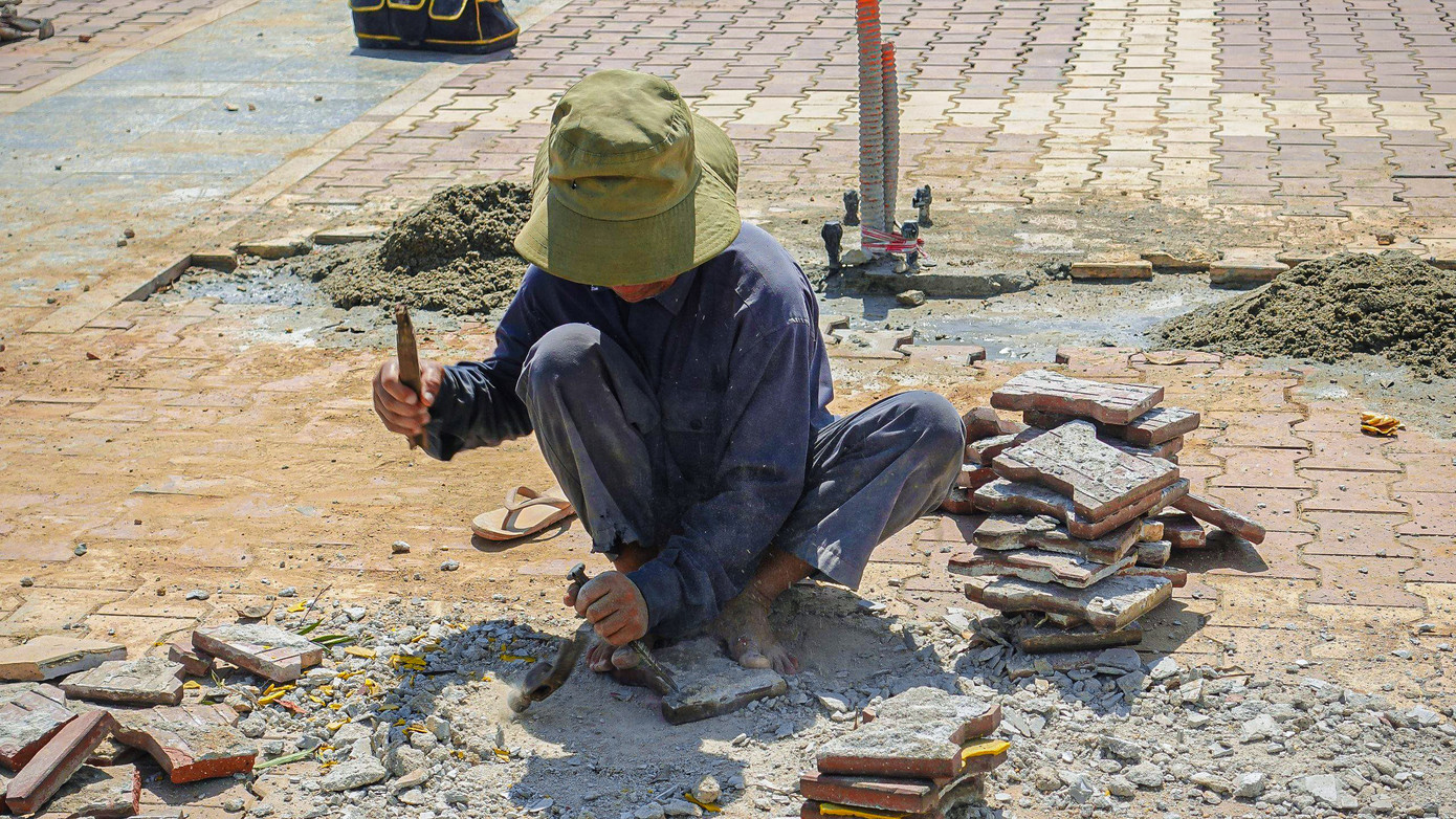 Công nhân đang tiến hành lát gạch, thi công những hạng mục tại vỉa hè phố đi bộ Bạch Đằng.