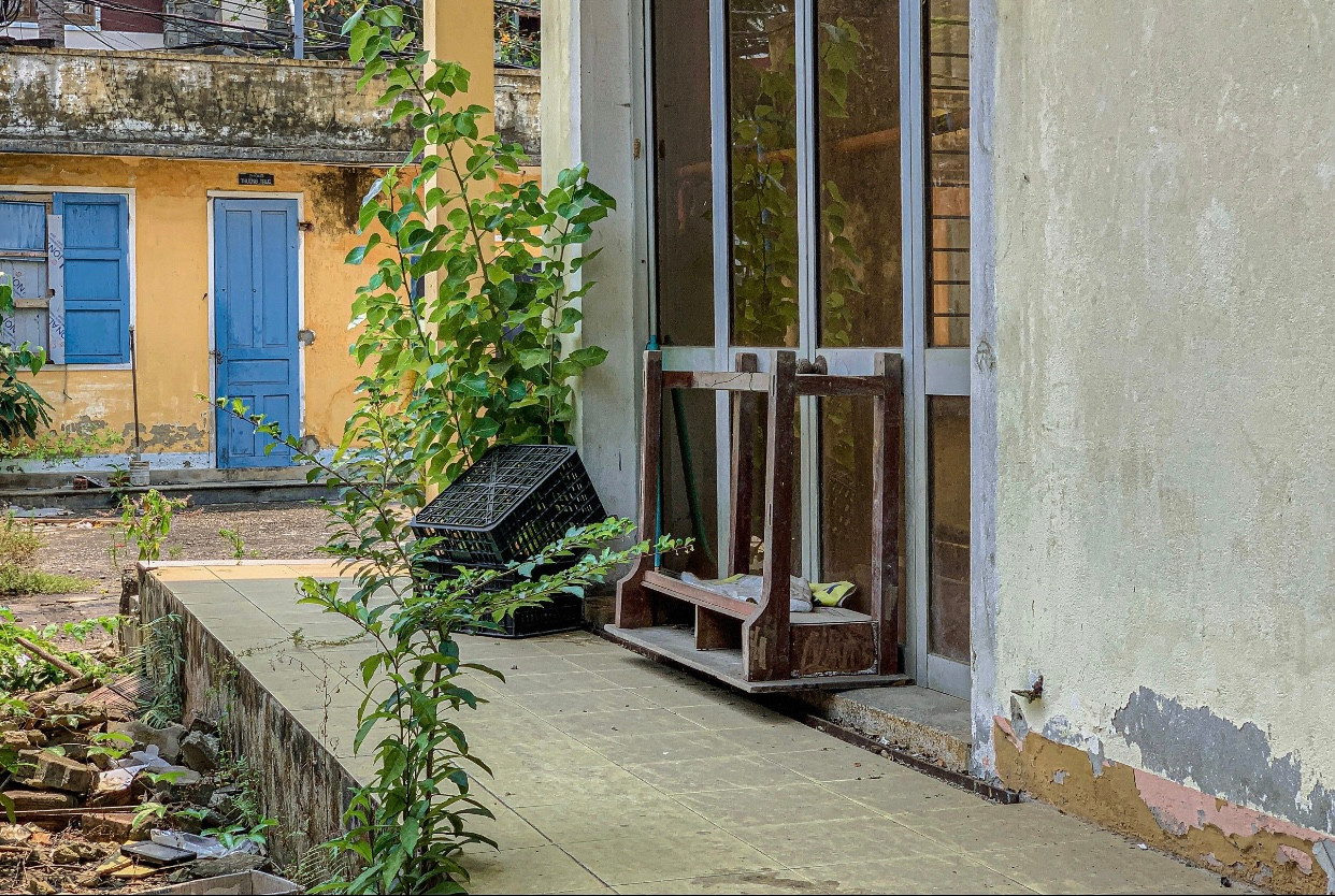 Phía bên ngoài hành lang nhiều bàn ghế vứt bừa bãi, lá cây phủ kín khuôn viên tạo nên khung cảnh nhếch nhác, hoang tàn. Phía bên ngoài hành lang nhiều bàn ghế vứt bừa bãi, lá cây phủ kín khuôn viên tạo nên khung cảnh nhếch nhác, hoang tàn.