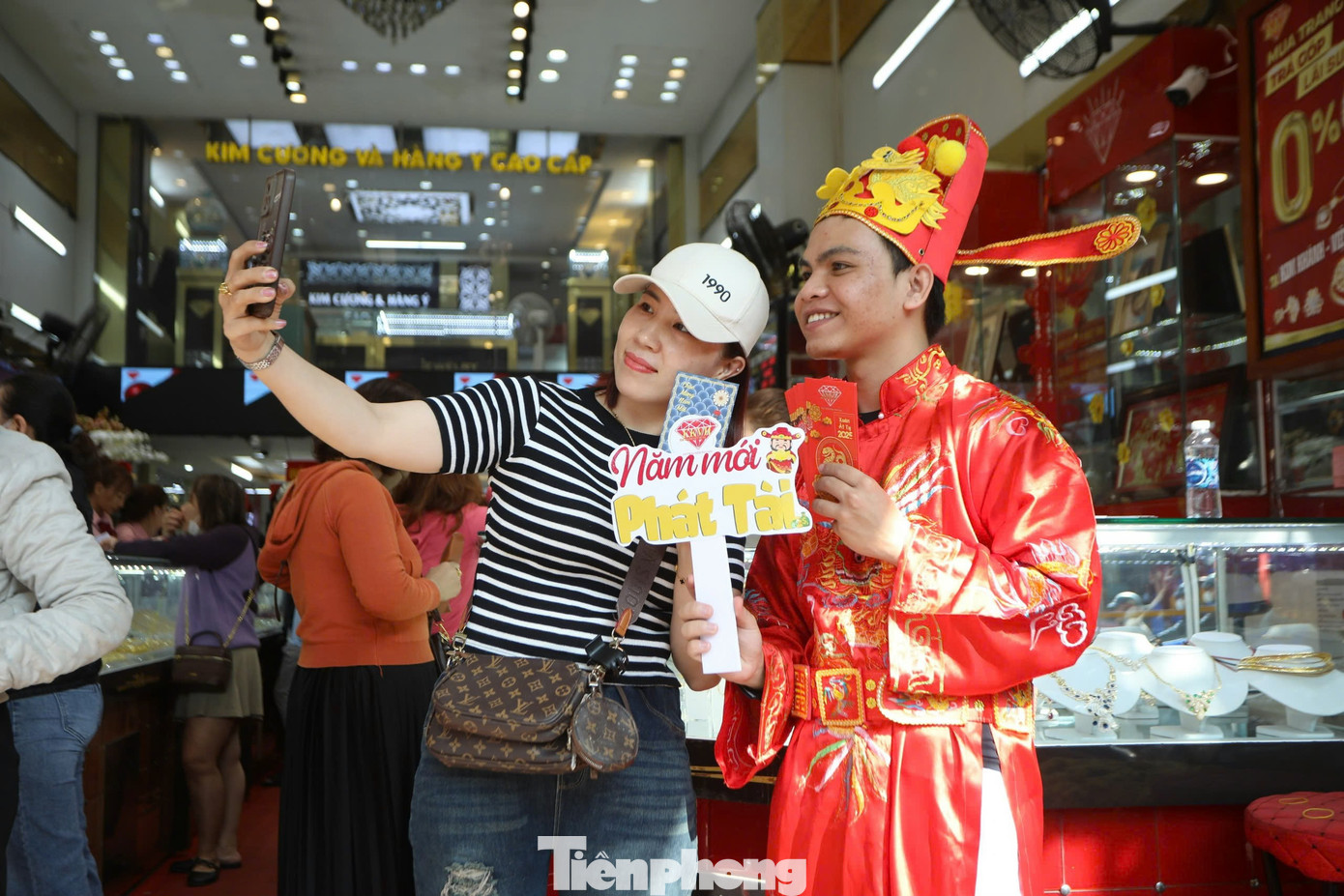 Nhiều người vui vẻ nhận lì xì, chụp hình cùng thần tài sau khi mua vàng để cầu may mắn trong năm mới.
