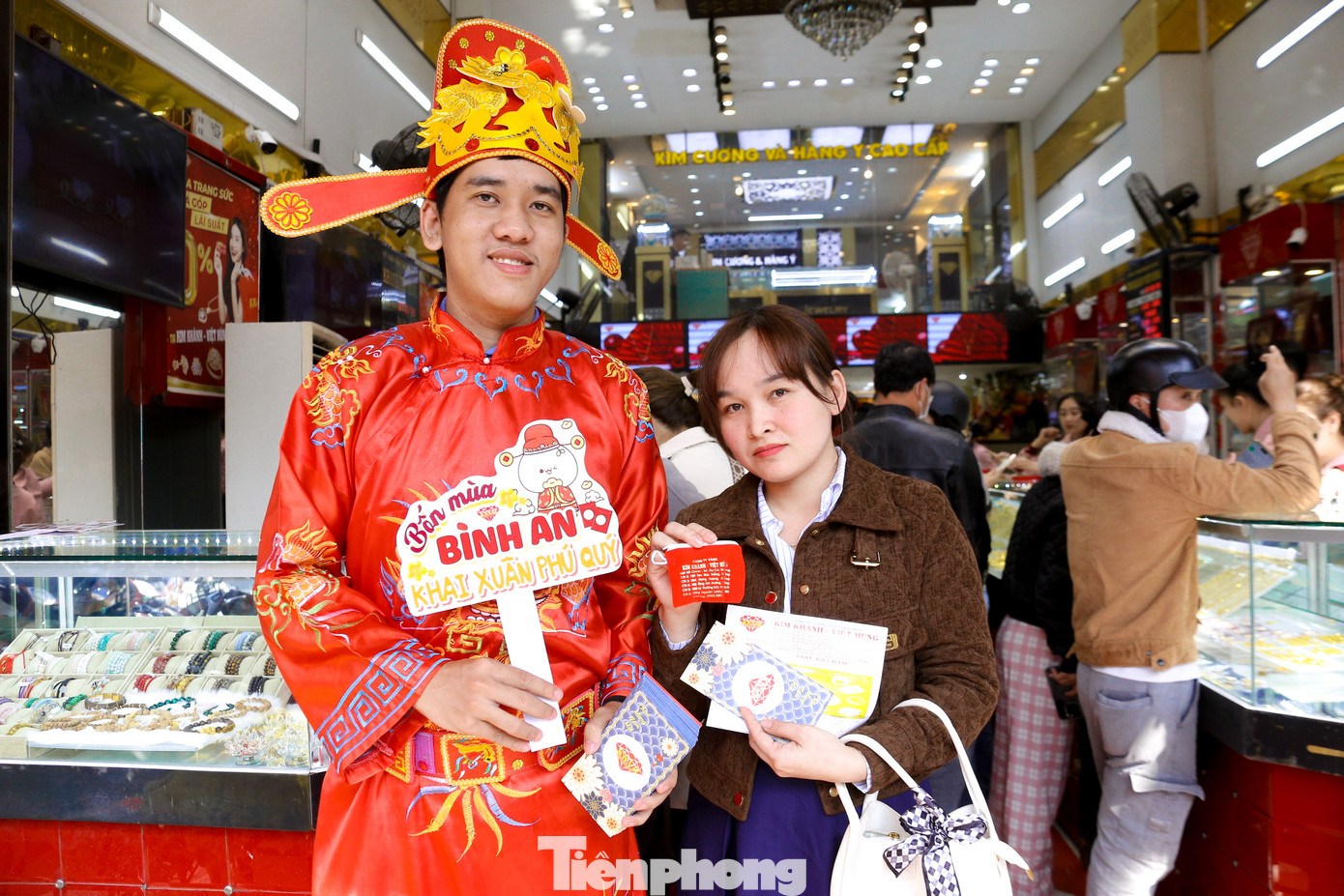 Nhiều người vui vẻ nhận lì xì, chụp hình cùng thần tài sau khi mua vàng để cầu may mắn trong năm mới.