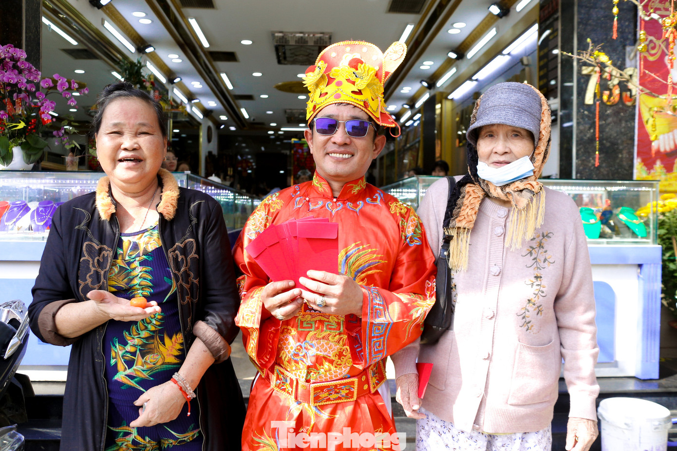 Nhiều người vui vẻ nhận lì xì, chụp hình cùng thần tài sau khi mua vàng để cầu may mắn trong năm mới.