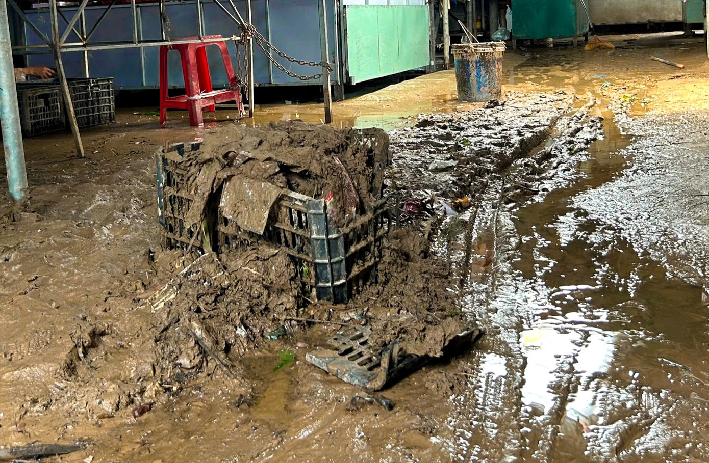 Theo ghi nhận tại chợ trong ngày 6/7, khu vực xung quanh chợ còn lầy lội, nhiều vũng nước đọng lại. Bên trong chợ, các tiểu thương tất bật nạo vét bùn đất, lau rửa quầy kệ và phân loại lại hàng hóa còn sử dụng được.