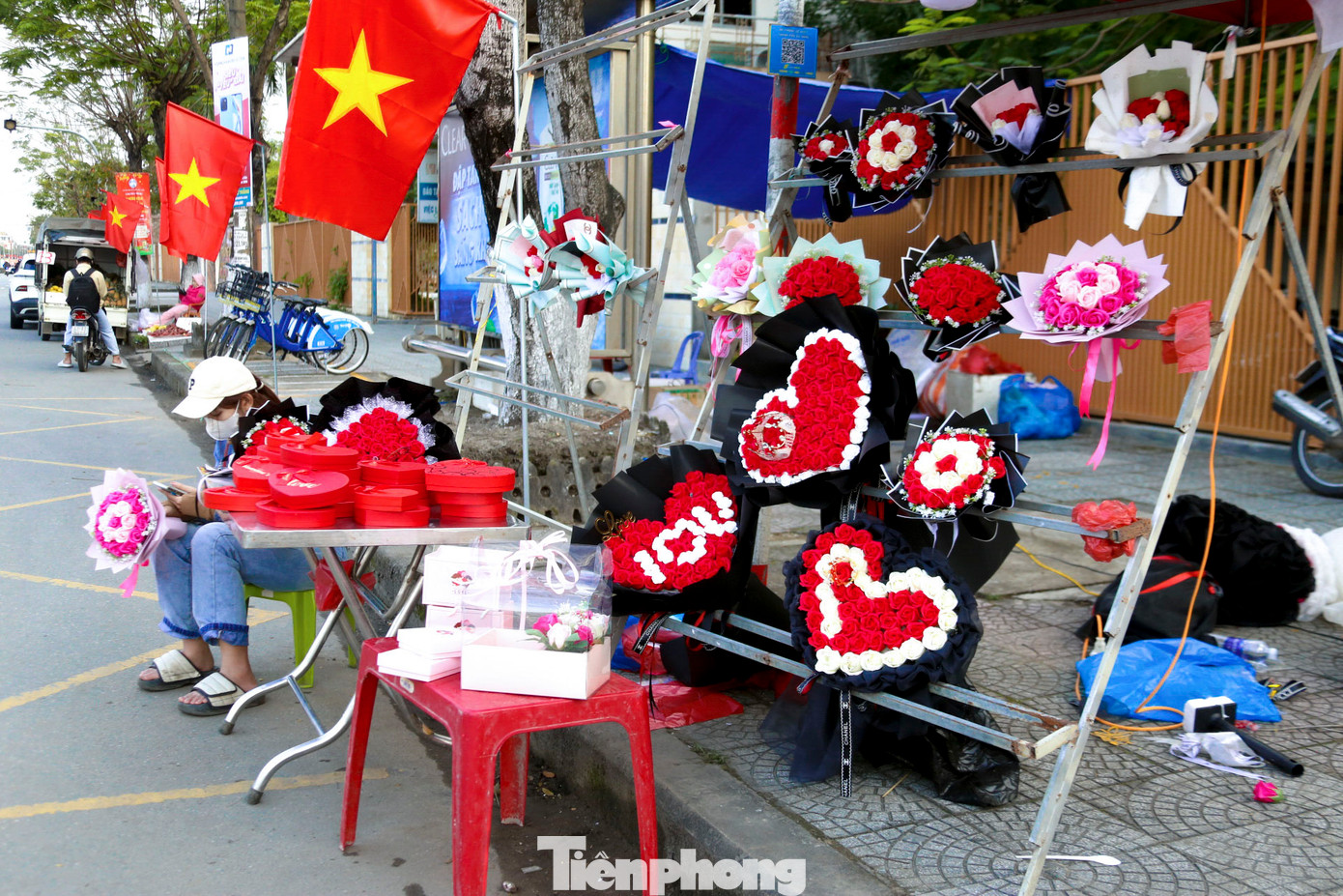 Nhiều người ngồi đợi khách đến mua hoa, quà ngày lễ Valentine.