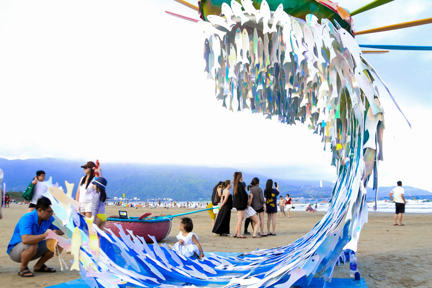 Tác phẩm "Sóng cá" gây ấn tượng mạnh với hơn 1.600 con cá làm từ meca và gỗ, phủ tông xanh đại dương, xếp thành dòng chảy uyển chuyển như biểu tượng cho những ước mơ và khát vọng hồi sinh từ biển cả.