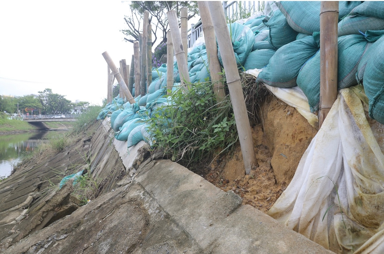 Cọc tre, bao cát được lực lượng chức năng gia cố tạm thời, hạn chế sạt lở lan rộng.