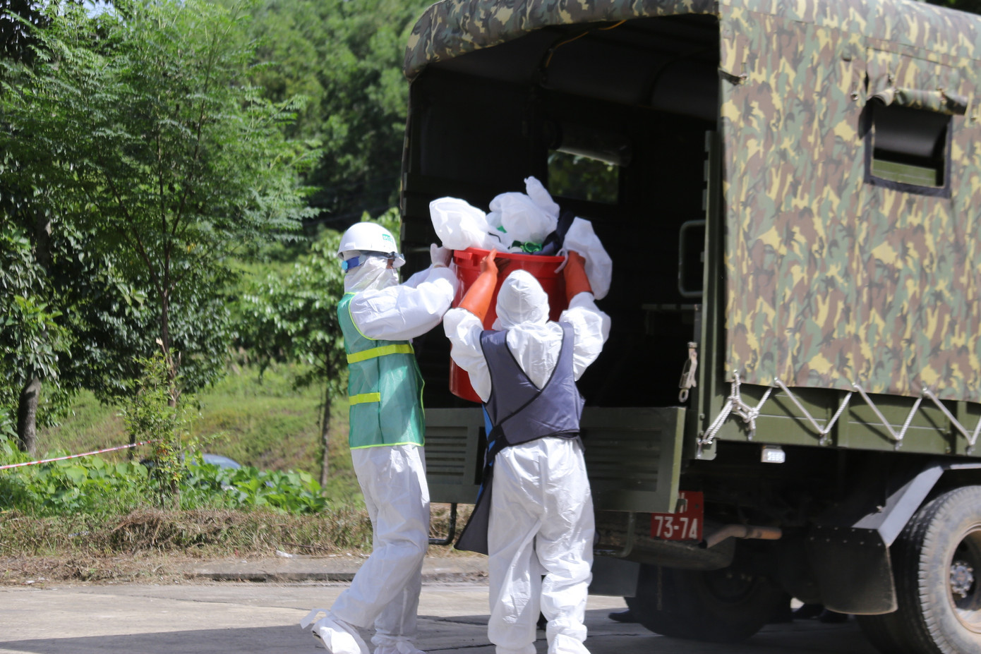 Sau khi kết thúc tẩy xạ, các lực lượng ứng phó hiện thu nguồn phóng xạ và di chuyển các thùng chì chứa chất nhiễm phóng lên xe và đưa đi xử lý.