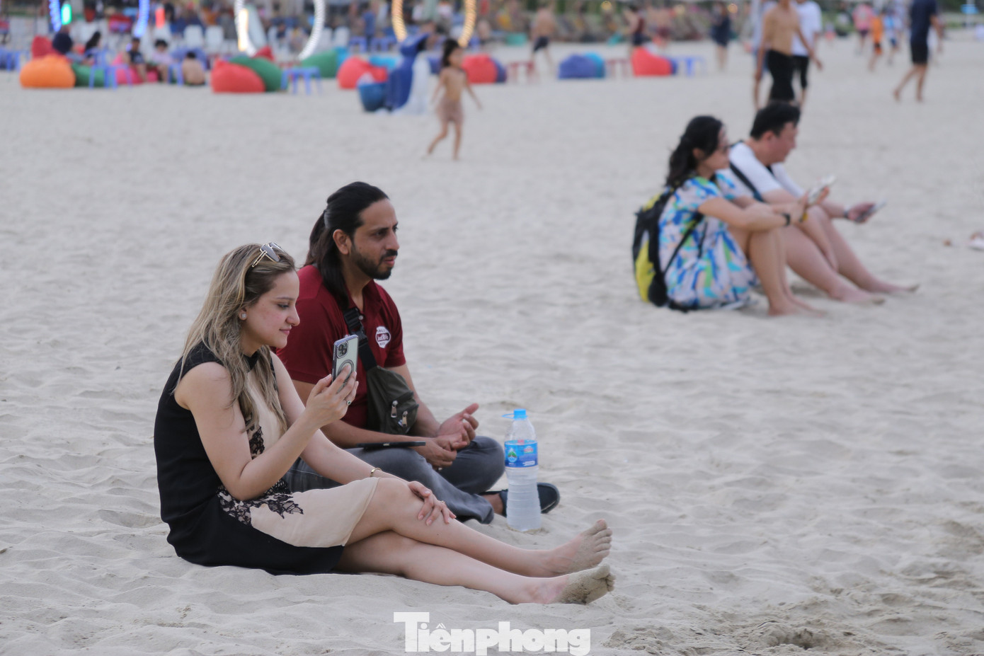 Nhiều du khách nước ngoài ngồi hóng gió trên bãi biển.