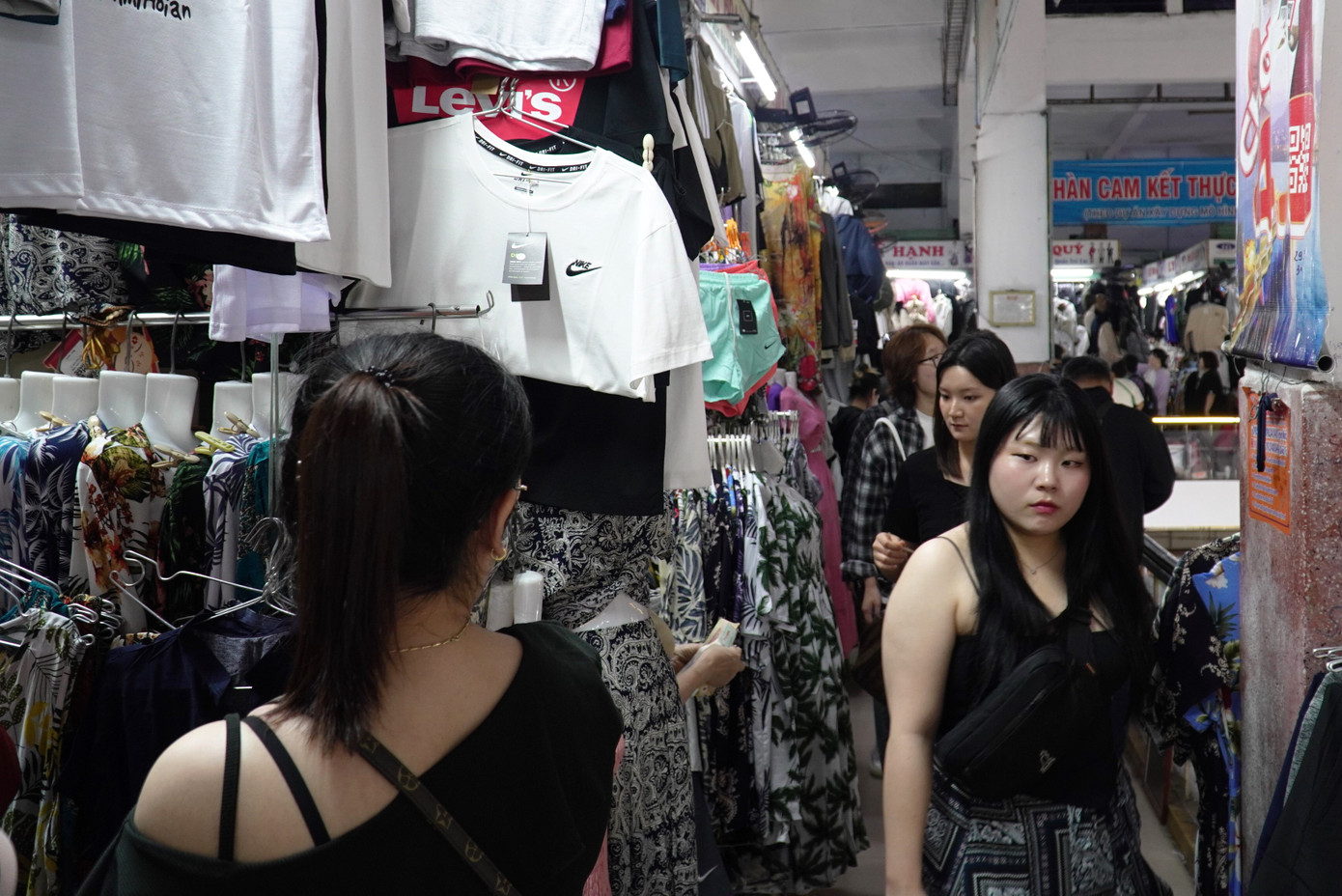 Du khách nối nhau lên tầng hai mua sắm quần áo, giày dép. Các lối đi chật kín, phải nép người nhường nhau. Các tiểu thương chia sẻ hiện các loại giày, dép đi mưa bán chạy hơn do Đà Nẵng mưa liên tục. Ảnh: Thanh Hiền.