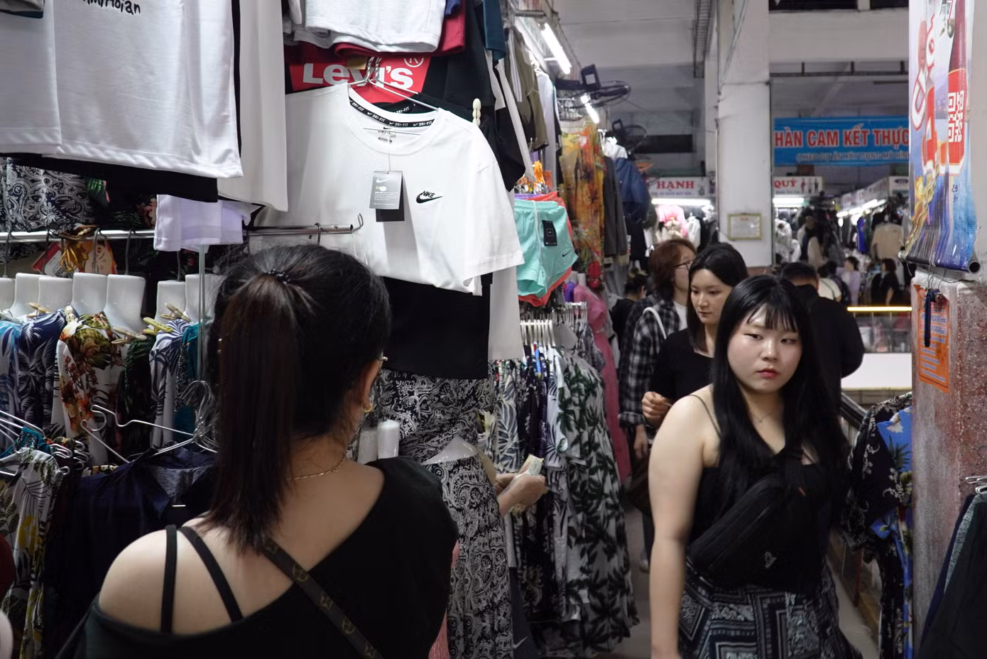 Du khách nối nhau lên tầng hai mua sắm quần áo, giày dép. Các lối đi chật kín, phải nép người nhường nhau. Các tiểu thương chia sẻ hiện các loại giày, dép đi mưa bán chạy hơn do Đà Nẵng mưa liên tục. Ảnh: Thanh Hiền.