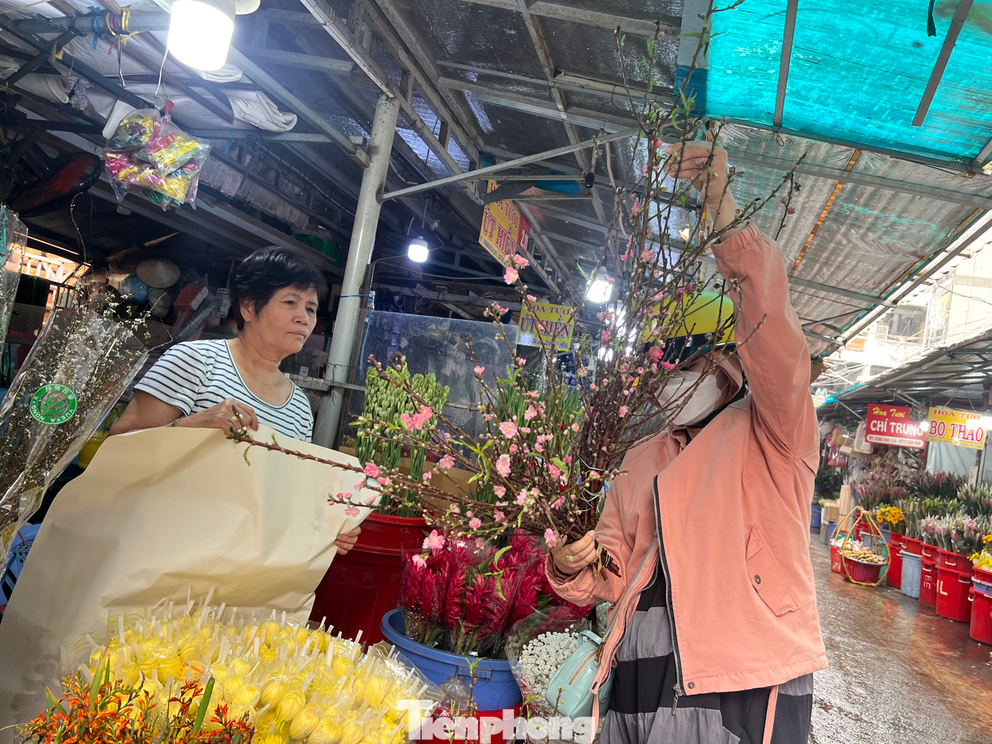 Ba ngày qua, bà Đặng Thị Phượng (bìa trái), sạp 2.9 chợ hoa Hồ Thị Kỷ (quận 10, TPHCM) đã bắt đầu nhập những cành đào mini ở phía Bắc vào bán sớm cho khách hàng ở thành phố. "Mỗi ngày tôi bán được vài chục cành đào mini với giá 130.000 đồng/cành. Đào cành đi máy bay, thời gian từ lúc cắt tại vườn khi đến tay khách chỉ trong ngày nên rất tươi mới" - bà Phượng cho biết.