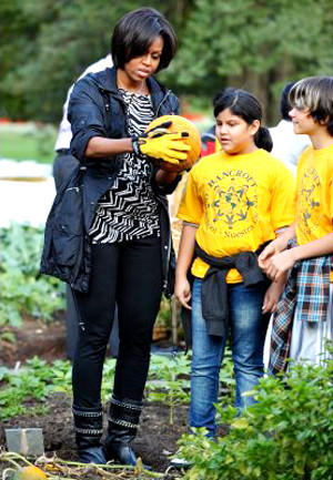 Bà Obama rạng rỡ cầm quả bí ngô vàng rực trên tay. Bà Obama rạng rỡ cầm quả bí ngô vàng rực trên tay