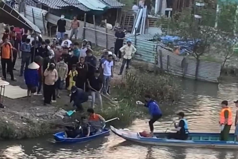 Người dân và lực lượng chức năng đưa thi thể bé K. lên bờ. Ảnh: A.H Người dân và lực lượng chức năng đưa thi thể bé K. lên bờ. Ảnh: A.H