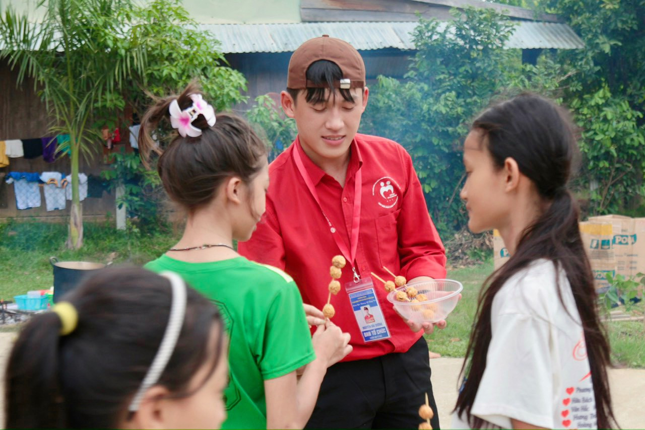 Dương đang chia các xiên cá viên chiên cho các em nhỏ tại Chương trình Thanh niên tình nguyện hè "Mang yêu thương về vùng cao" năm 2024.