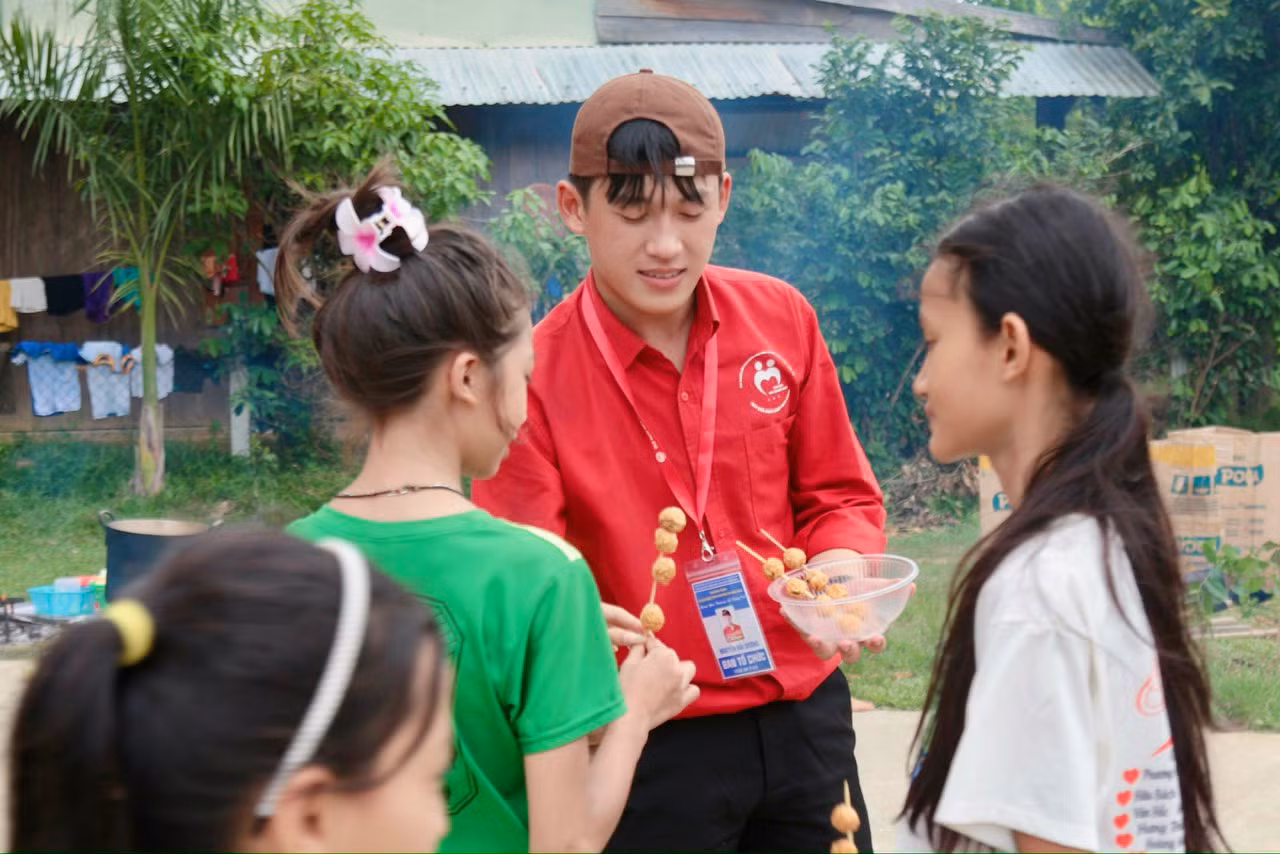 Dương đang chia các xiên cá viên chiên cho các em nhỏ tại Chương trình Thanh niên tình nguyện hè "Mang yêu thương về vùng cao" năm 2024.