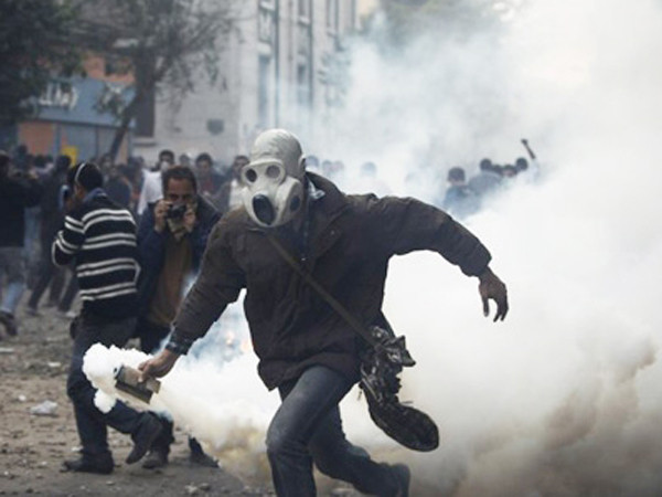 Một người biểu tình ném trả lựu đạn cay về phía cảnh sát. Ảnh: AP