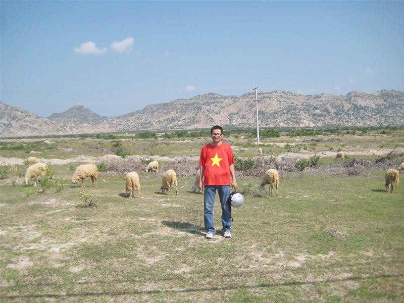 Thạch đứng giữa cánh đồng khô cháy ở Ninh Thuận, sau lưng là những cánh rừng đã bị triệt hạ chỉ còn núi đá